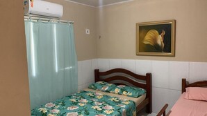 A small bedroom with a single bed, a shower curtain, a wall-mounted air conditioner, and a framed painting. - Spacious and airy house in Japaratinga, pets allowed. (Japaratinga)