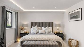 Een slaapkamer met een groot bed, nachtkastjes, een raam en een ingelijst beeld aan de muur.