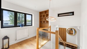 En modern inredning med stora fönster, en trätrappa och en inbyggd bokhylla.