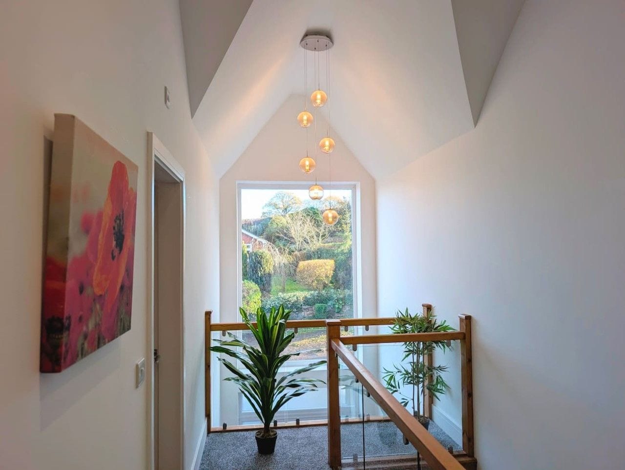 Ein modernes Interieur mit einer Treppe, einem großen Fenster und einer hängenden Leuchte.