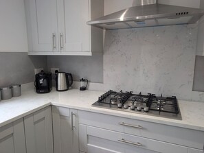 A modern kitchen with a gas stove, coffee maker, and kettle. - Family Affair: fun for all in this spacious home (Hanwood)