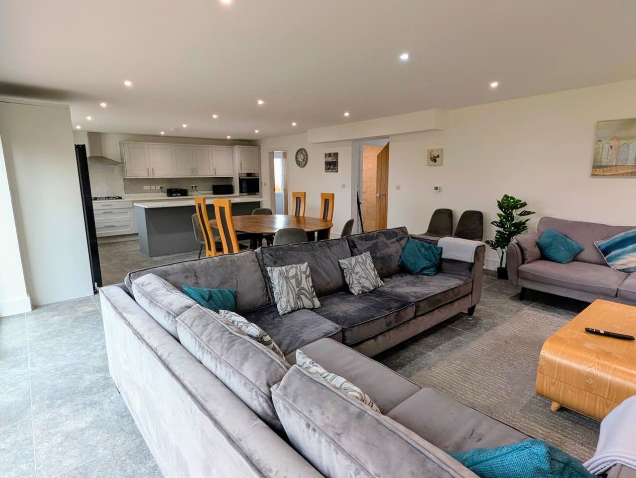 A modern living room with a sectional sofa, a coffee table, and a dining area in the background.