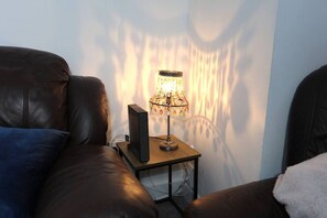 A room with a leather sofa, a small table with a lamp, and a wall-mounted speaker. - Contractor House, 4 Bed Ensuite, Near Stadium (West Midlands)