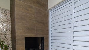 A bathroom with a tiled backsplash, a black countertop, a potted plant, a white door with horizontal blinds, and a vent. - Cozy house in Guarujá, 3km from the beach. Air conditioning/Wi-Fi/barbecue. (Guarujá)