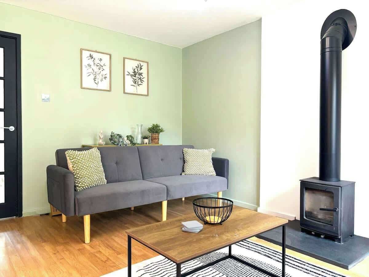 A living room with a sofa, a coffee table, a fireplace, and framed wall art.