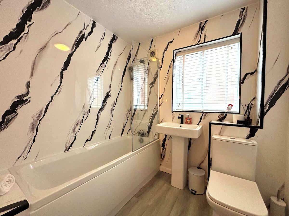 Une salle de bain avec un mur en marbre, une baignoire, un lavabo et des toilettes.