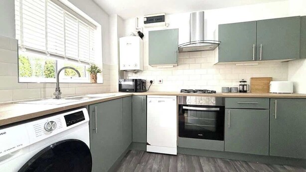 Una cucina compatta con lavatrice, forno a microonde, piano cottura e forno incassato.