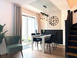 A modern dining area with a table, chairs, and a clock on the wall.