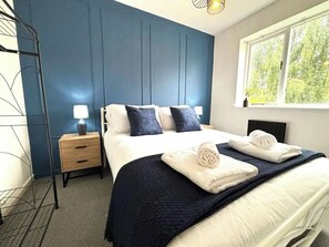 A hotel room with a bed, bedside tables, and a window with a view of greenery.