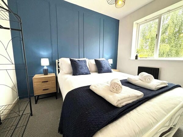 A hotel room with a bed, bedside tables, and a window with a view of greenery.