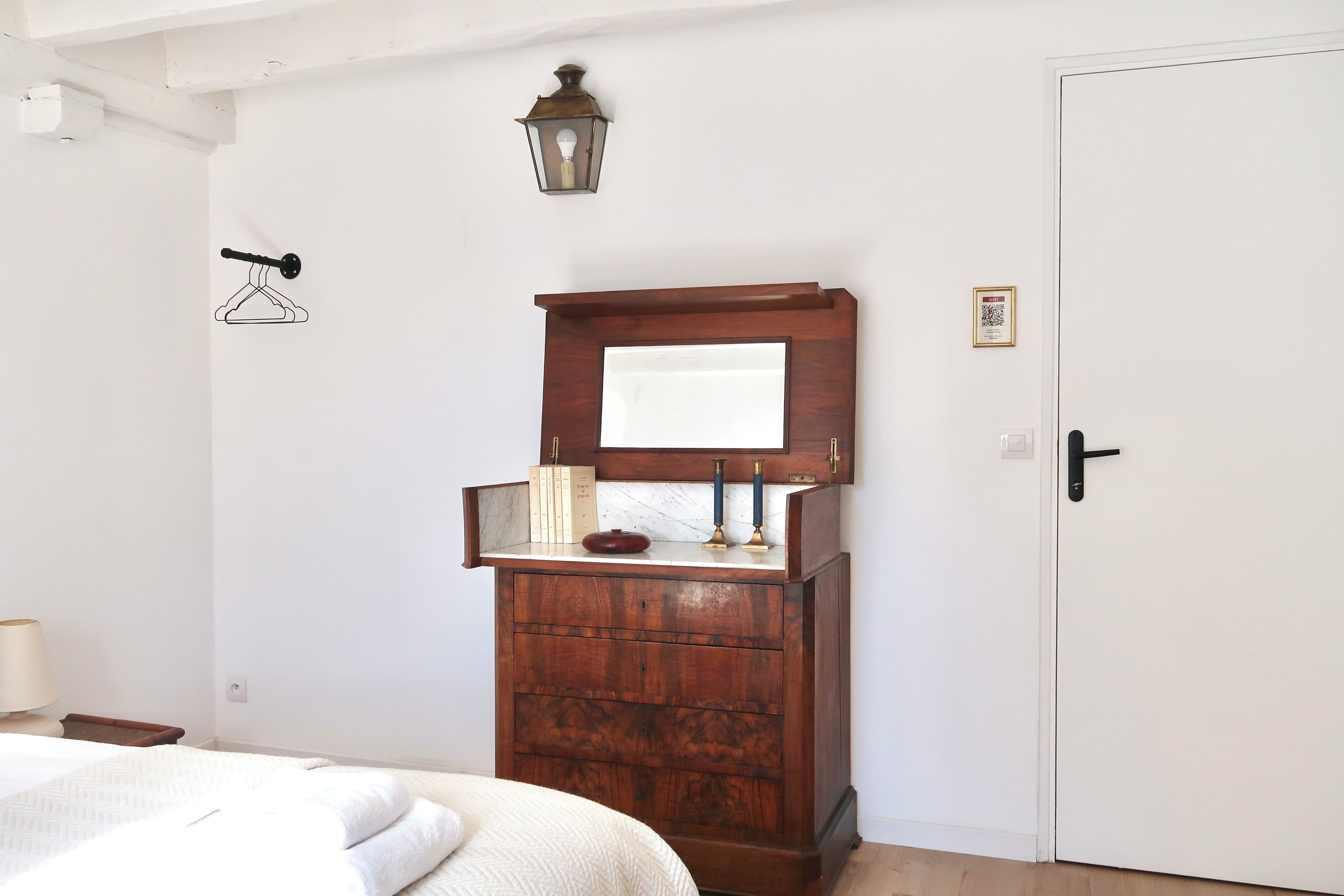 Une chambre avec une armoire en bois, un luminaire suspendu et une porte sur laquelle est apposé un symbole indiquant la présence d’une connexion Wi-Fi.