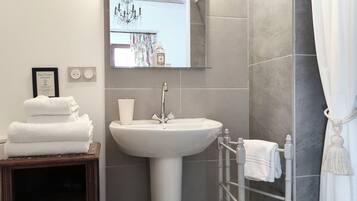 A bathroom with a white sink, a mirror, a towel rack, and a framed sign on the wall.