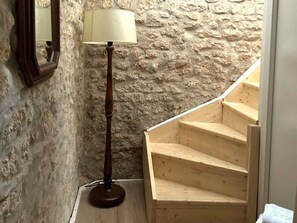 A wooden staircase with a textured stone wall.