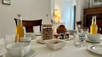 Ontbijttafel gedekt met verschillende soorten eten, waaronder een fles, een pot granola en meerdere kleine bakjes met spreads.