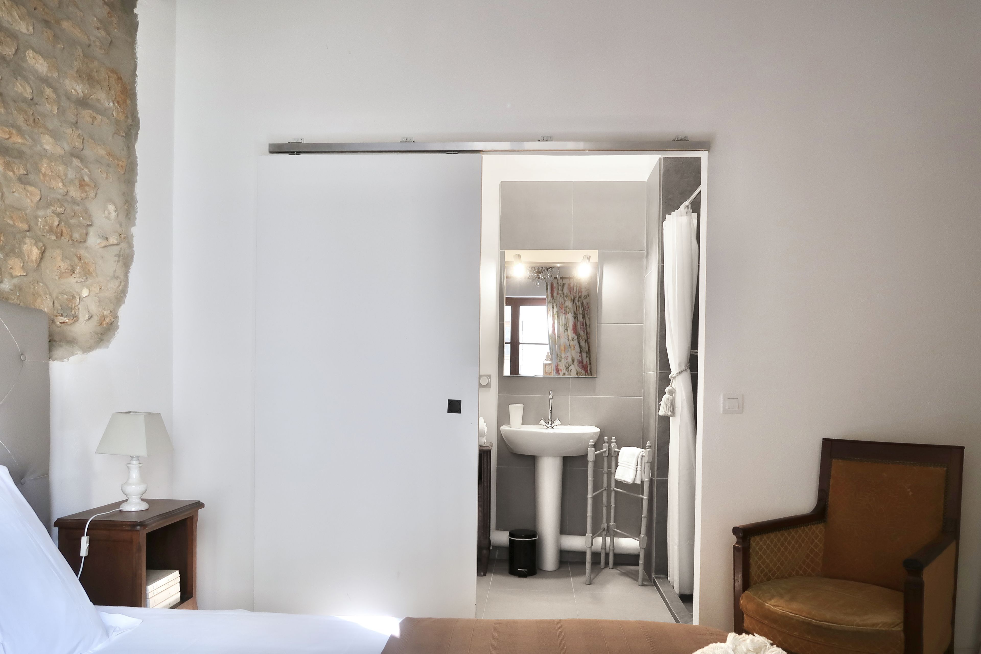 Un dormitorio con una cama, una mesita de noche, una lámpara y una silla.