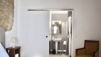 Un dormitorio con una cama, una mesita de noche, una lámpara y una silla.