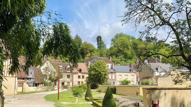 A rural village with traditional houses, a gravel path, and a small park area with a bench and a fire hydrant. - La grange à grains (Château-Renard)