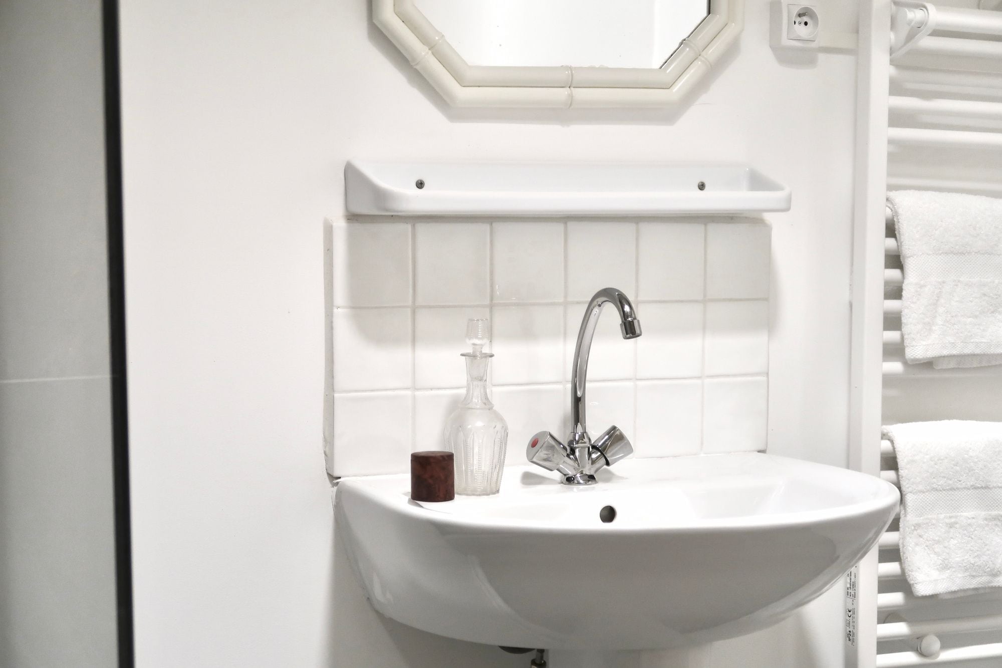 A bathroom with a white sink, a mirror above it, and a towel rack to the right.