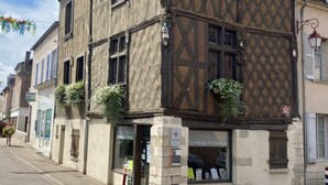 A traditional half-timbered building with a shop entrance and a visible sign for 'Syndicat d'Initiative'. - La grange à grains (Château-Renard)