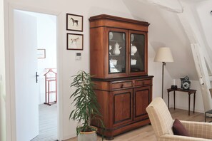 Une pièce comprenant un meuble en bois, une chaise, une lampe et une plante en pot.