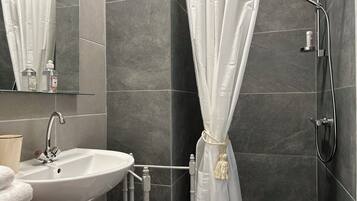 Een badkamer met een witte wastafel, spiegel en douche.