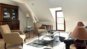 A spacious loft with high ceilings, a dining area, and a view of the sky through a skylight. - La grange à grains (Château-Renard)