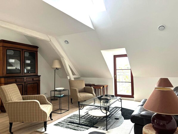 A spacious loft with high ceilings, a dining area, and a view of the sky through a skylight.