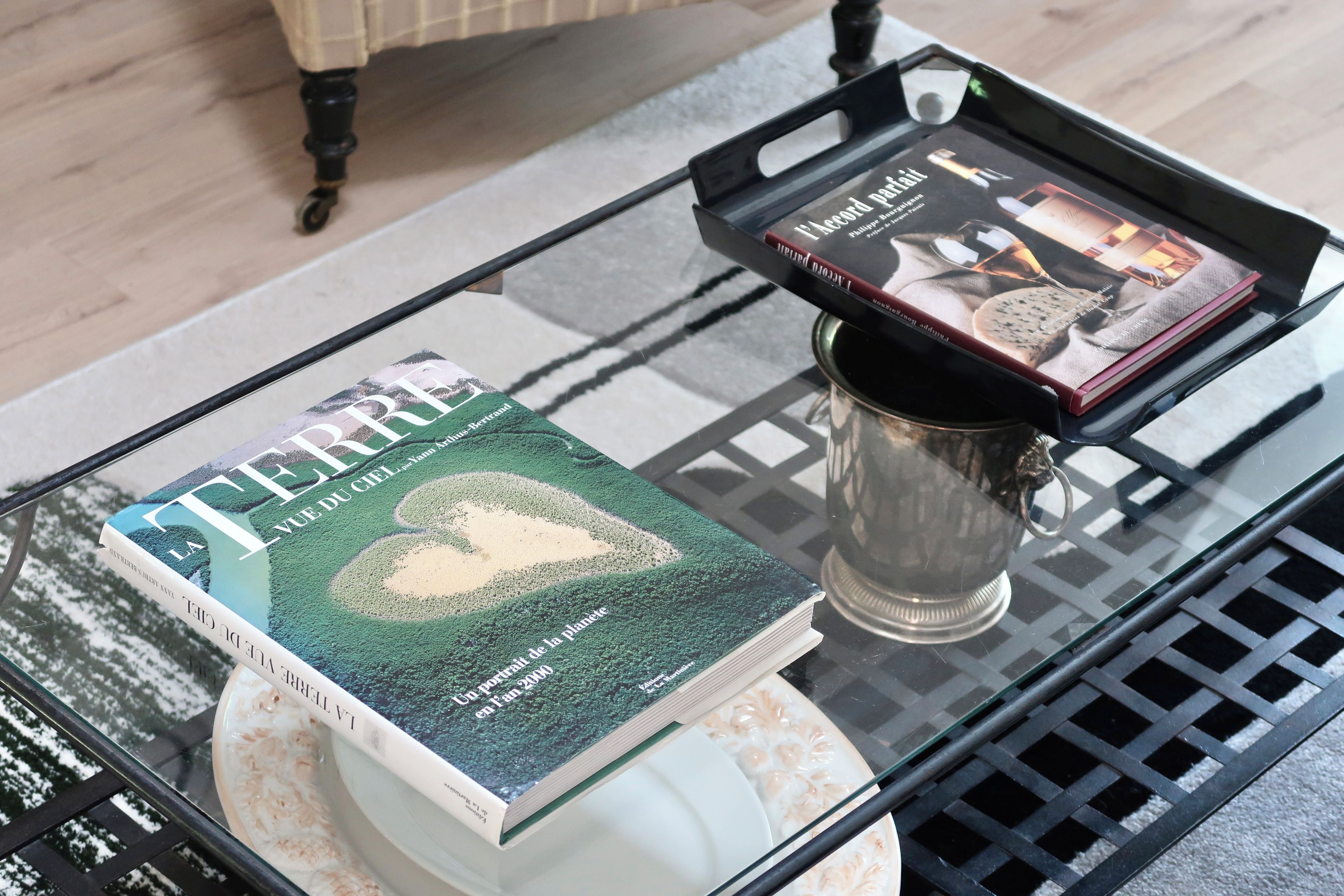 Ein Glastisch mit einem Buch mit dem Titel 'Terre' und einer dekorativen Tasse.