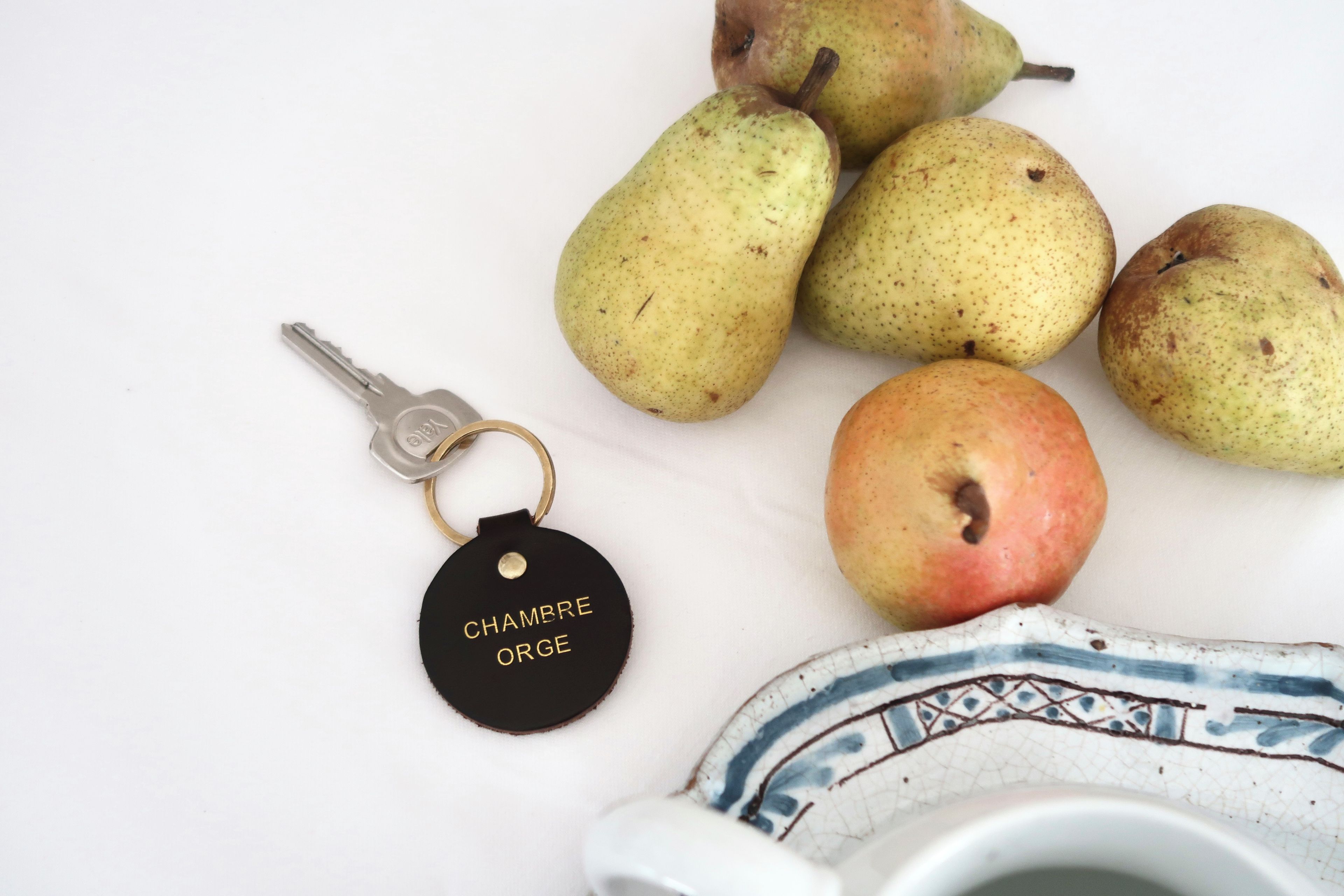 A collection of pears and an apple with a keychain labeled 'CHAMBRE ORGE' on a white surface.