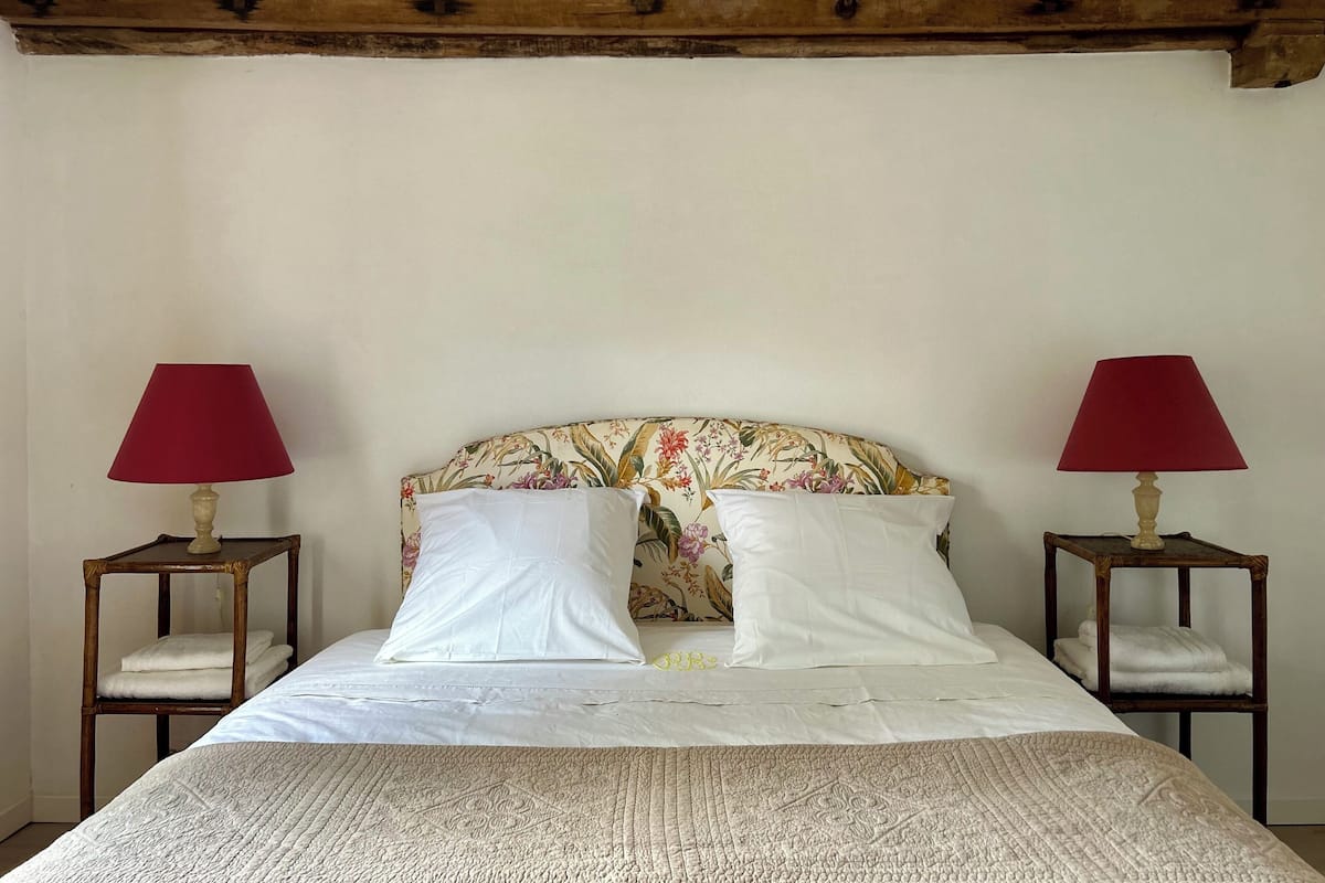 Een slaapkamer met een bed, twee nachtkastjes en een hoofdbord met bloemen.