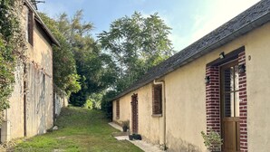 A narrow pathway leading to a row of traditional buildings with brick facades and wooden doors. - La grange à grains (Château-Renard)