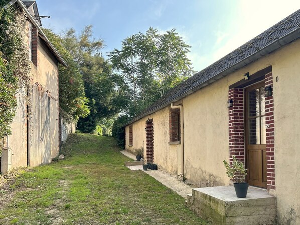 Un étroit sentier mène à une rangée de bâtiments traditionnels aux façades en briques et aux portes en bois.