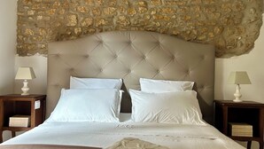 A bed with a tufted headboard, white bedding, and two bedside tables with lamps. - La grange à grains (Château-Renard)