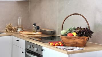 A kitchen with a wooden countertop, a stainless steel oven, and a basket of vegetables.