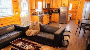 A cozy cabin interior with a living room, kitchen, and dining area.