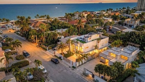 An aerial view of a residential area with a modern house featuring a rooftop deck, surrounded by palm trees and a beachfront. - Soleil Modern by Avantstay Design-forward Stay + Resort-style Pool + Hot Tub + Near the Beach (Fort Lauderdale)
