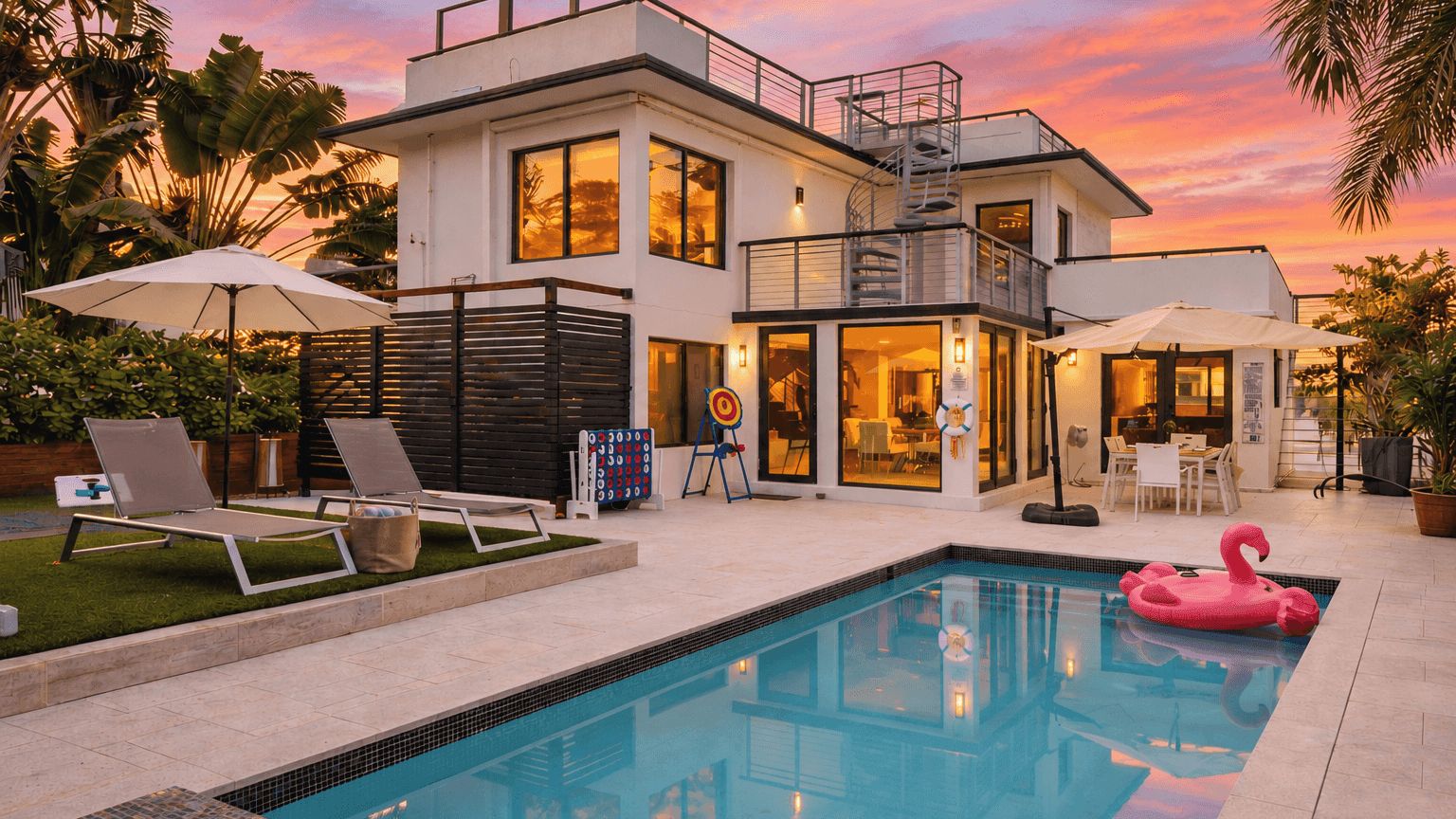 A modern two-story building with a swimming pool, outdoor seating, and a balcony.