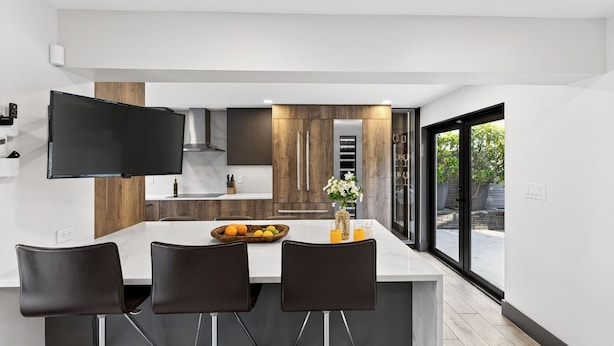 A modern kitchen with a central island, dark chairs, and a large window. - Soleil Modern by Avantstay Design-forward Stay + Resort-style Pool + Hot Tub + Near the Beach (Fort Lauderdale)