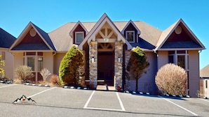 A two-story building with a stone facade, a central entrance with a number '27' above it, and a parking lot in front. - Reserve 27D • Big Skyline Views (Sugar Mountain)