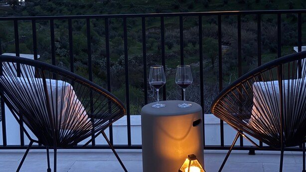 A balcony with two chairs, a table, and a lantern. In the background, there is a castle illuminated by warm lighting. - House in Belalcazar overlooking the Castle (Belalcázar)