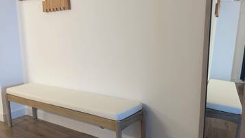 Un banco con cojín blanco, un adorno de pared de madera y un espejo con marco de madera.