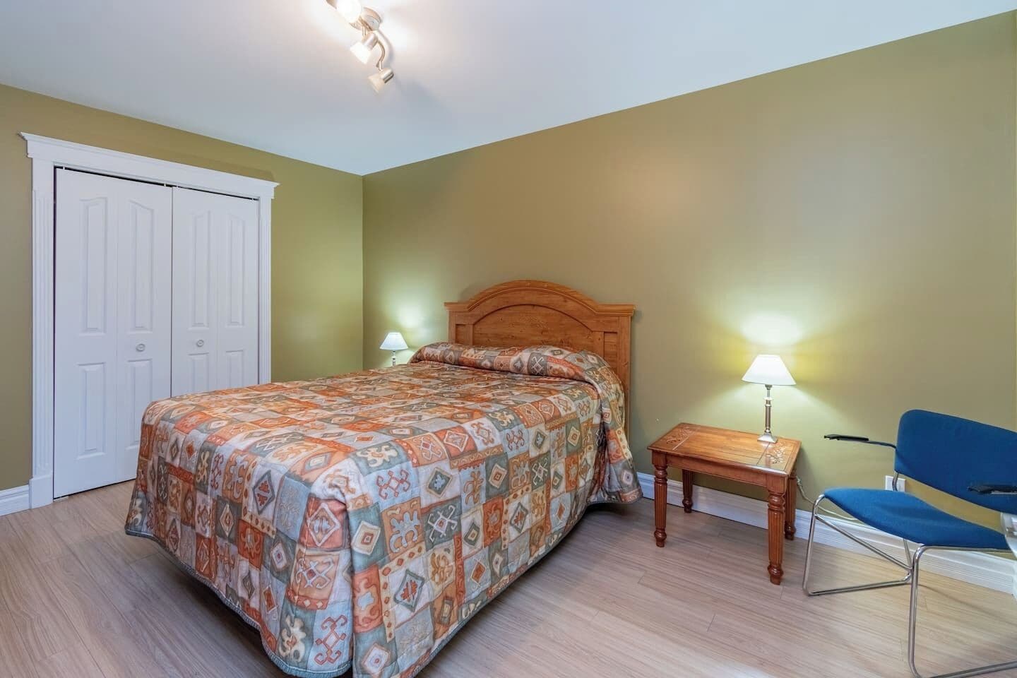 A bedroom with a bed, a nightstand, a chair, and a door.