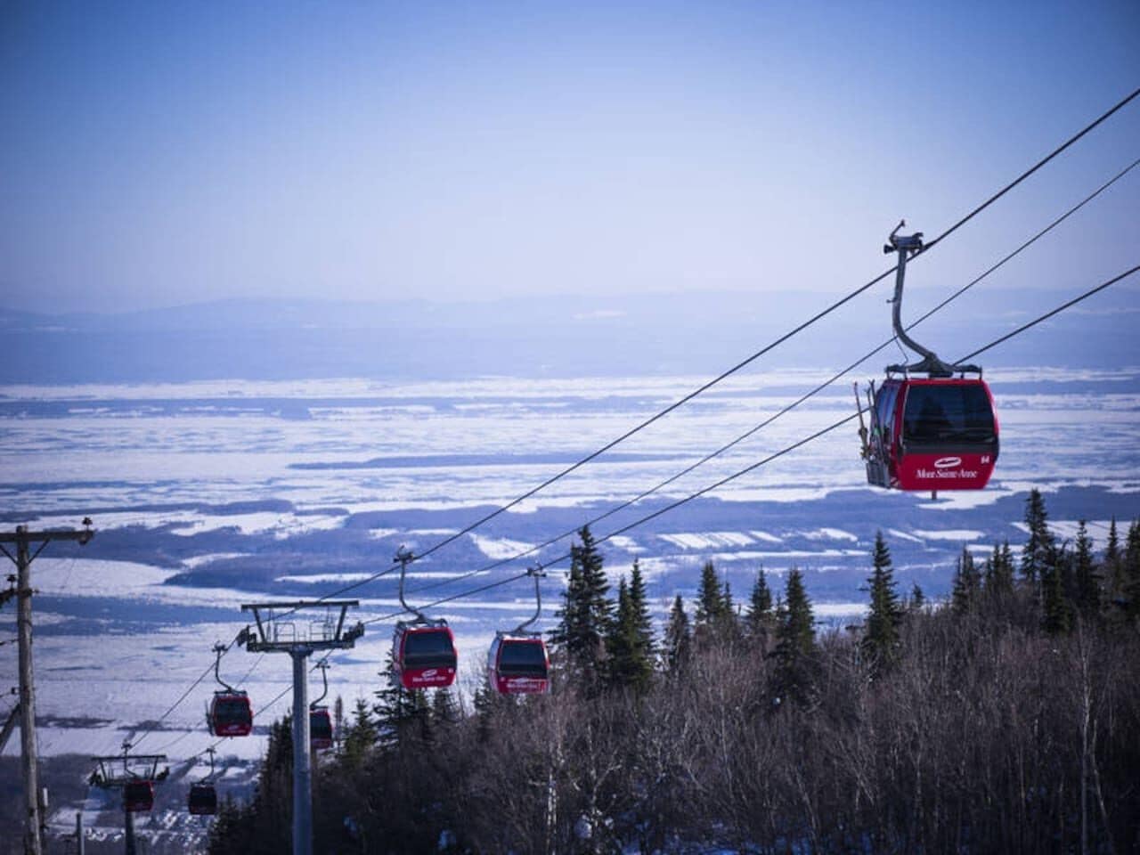 Ett linbanesystem med flera kabiner i ett snötäckt landskap.