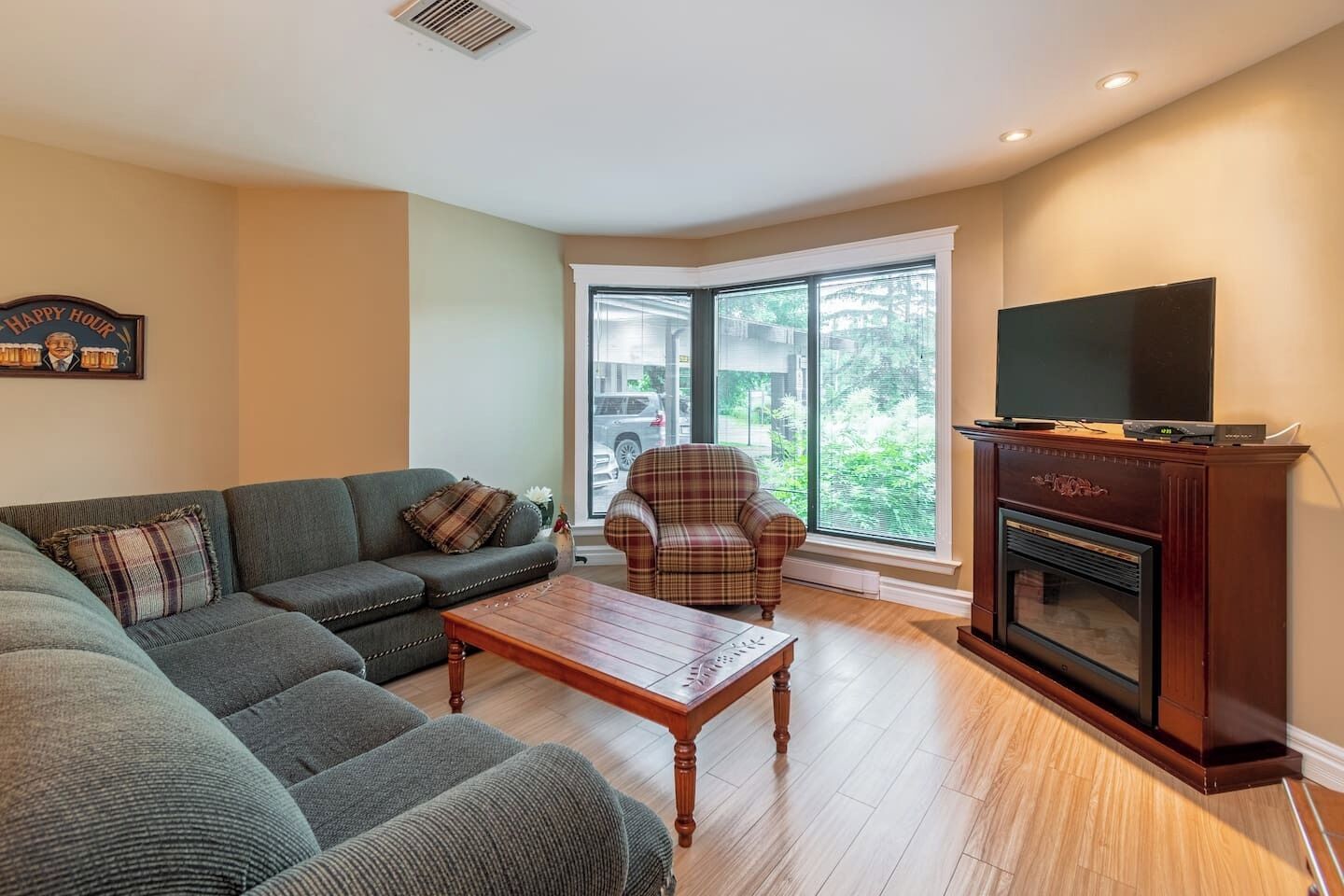 Una sala de estar con sofá, sillón, mesa de centro, chimenea y televisor.