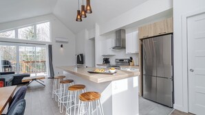 Cozinha moderna com uma ilha grande, eletrodomésticos de aço inoxidável e um espaço de jantar com banquetas.