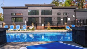 Um edifício moderno com piscina, espreguiçadeiras e área cercada.