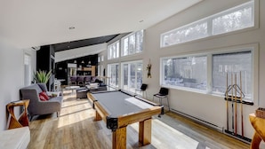 A spacious living area with a pool table, seating, and large windows. - 2CH: Relaxation + Spa + Sauna + BBQ + Wi-Fi (Pont-Rouge)