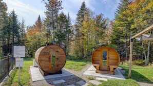 Two wooden sauna cabins in a forested area with a sign indicating no lifeguard on the pool. - 2CH: Relaxation + Spa + Sauna + BBQ + Wi-Fi (Pont-Rouge)