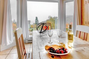 Ruokapöytä, jonka päällä on pullo Valle d'oro -viiniä, kaksi viinilasia ja lautanen täynnä hedelmiä.