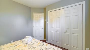 Un dormitorio con una cama, dos puertas blancas y piso alfombrado.